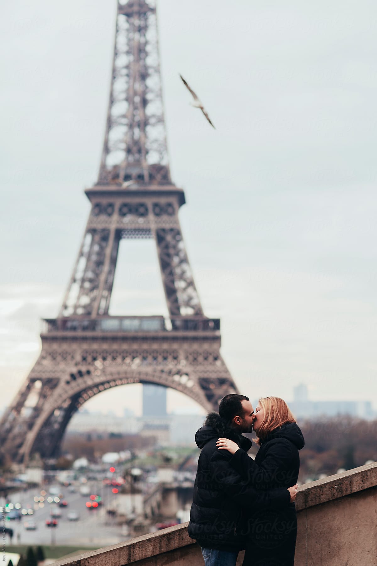 Happy Couple Kissing And Hugging In Front Of The Eiffel Tower In
