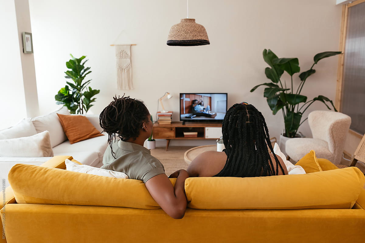 Black mom and daughter watching movie on TV