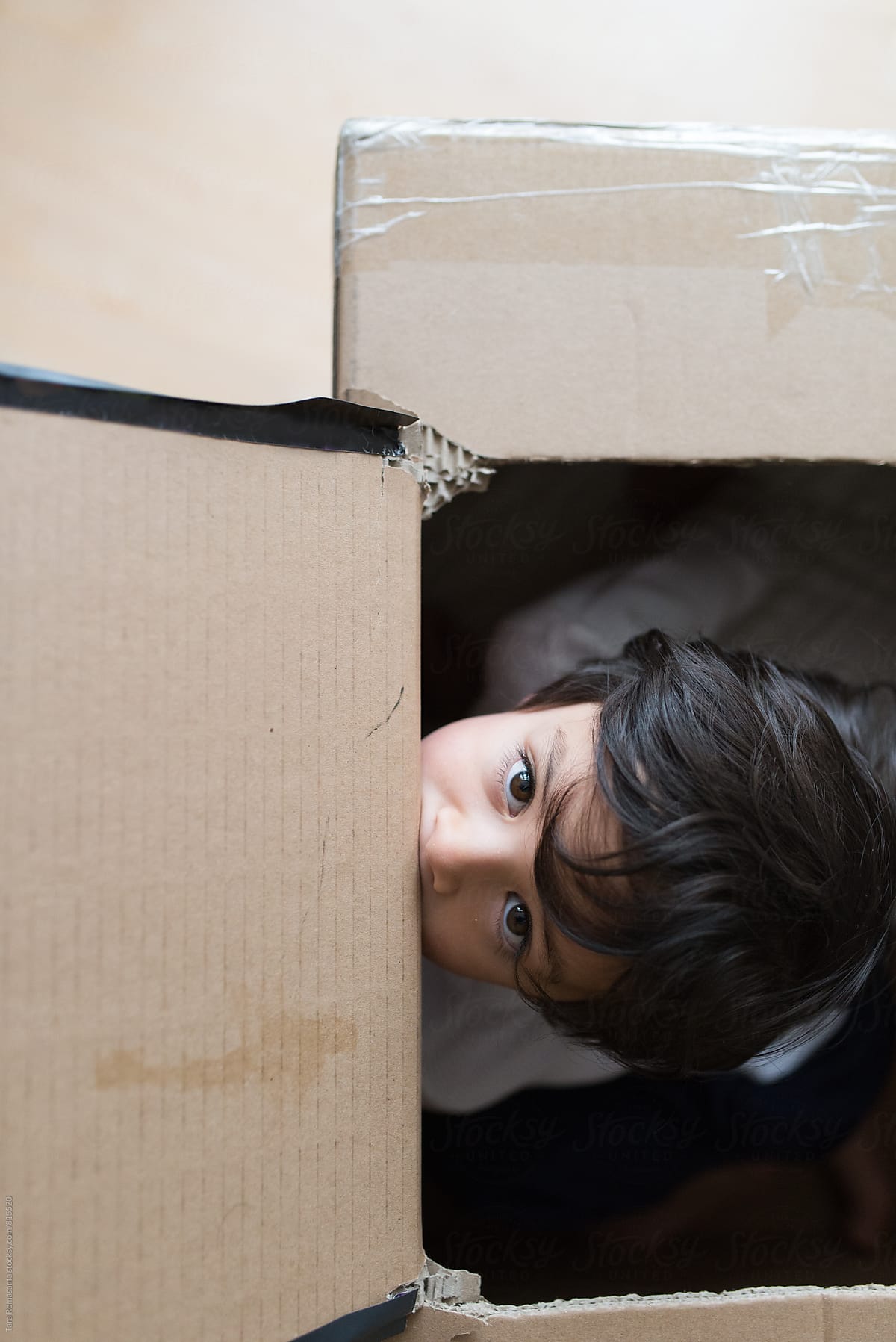 young child inside a box peeking out