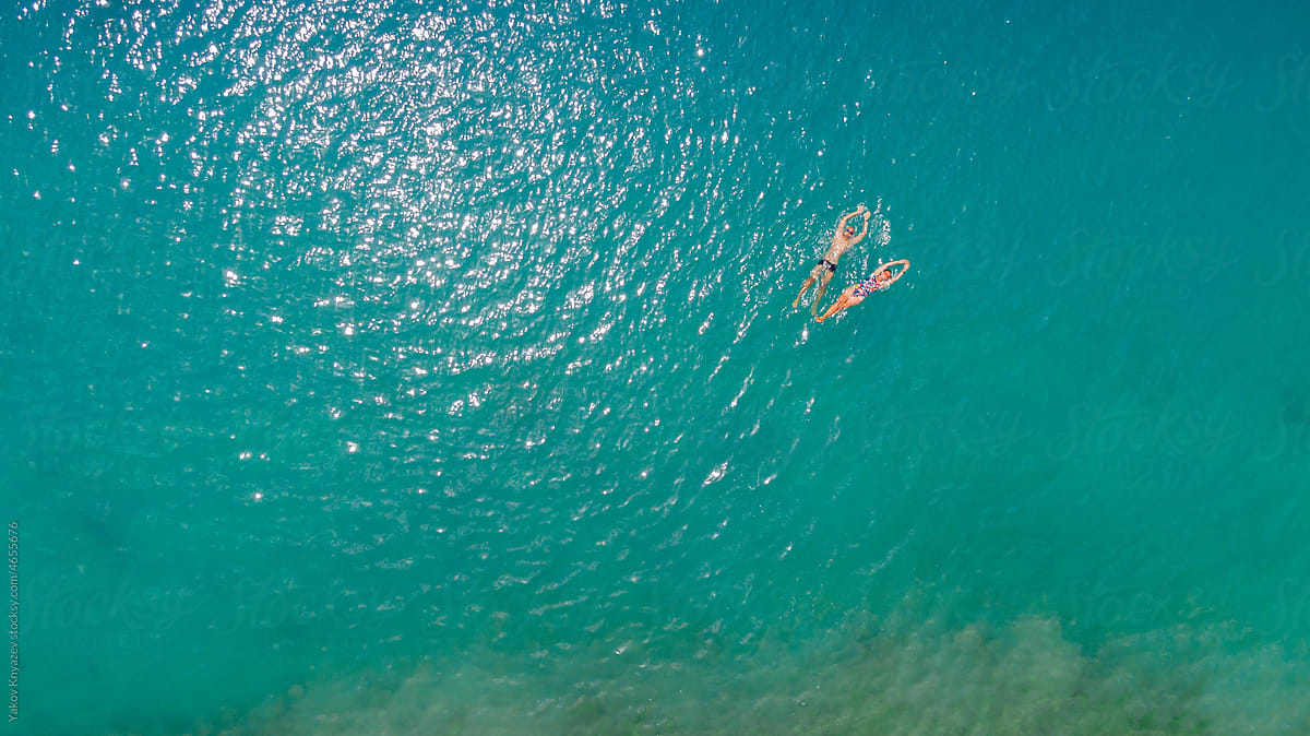 young man and woman swimming together in the sea, drone overhead