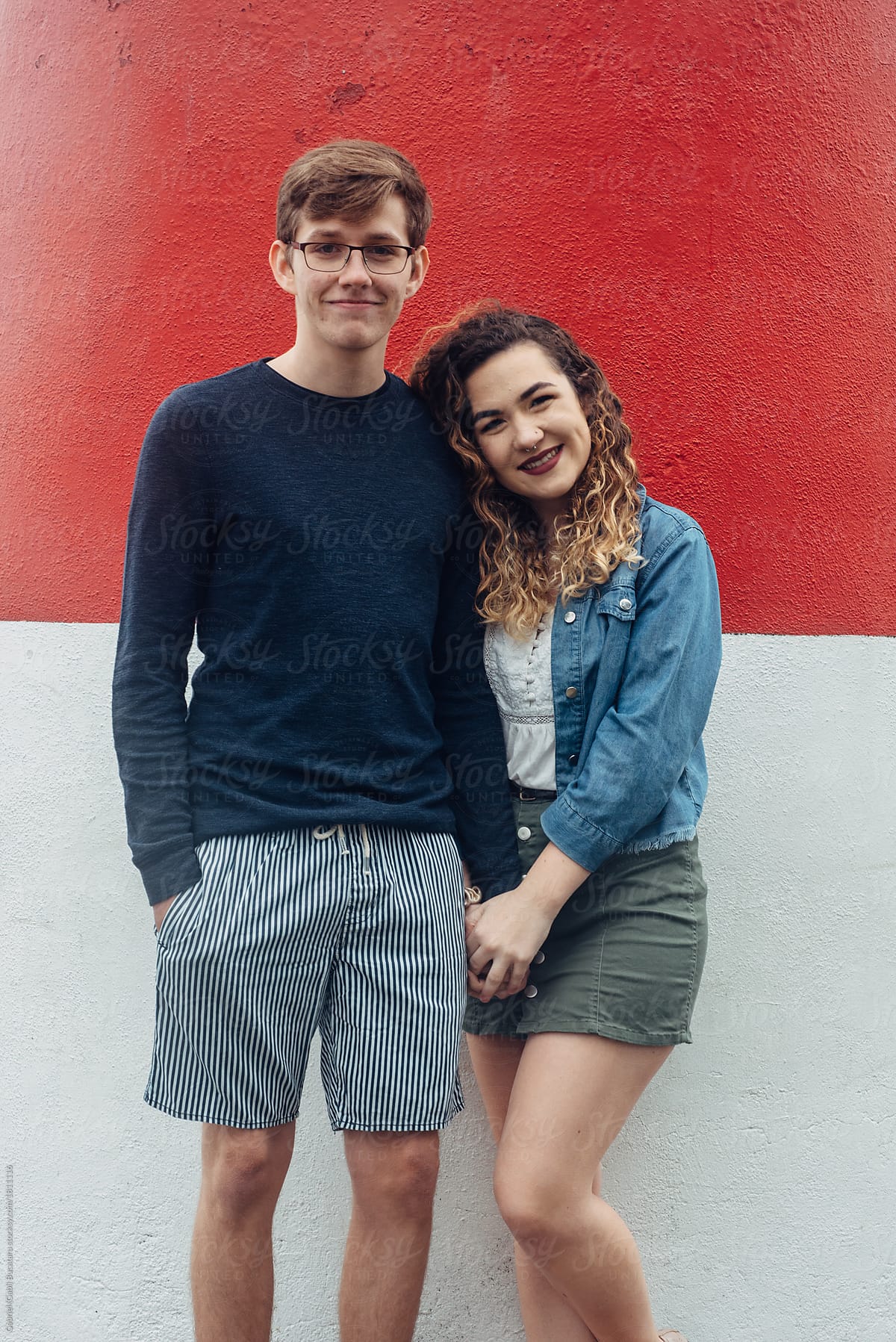Smiling couple by a red and white wall
