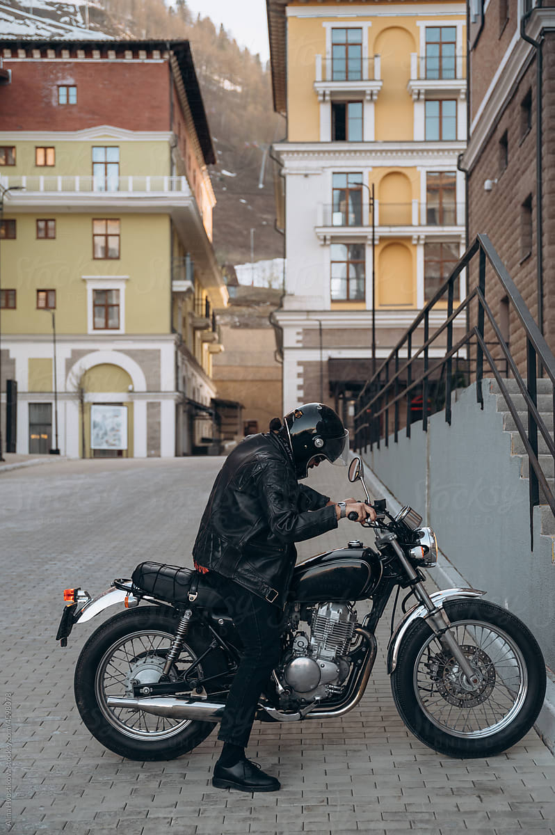 Male biker sitting on motorbike in old town