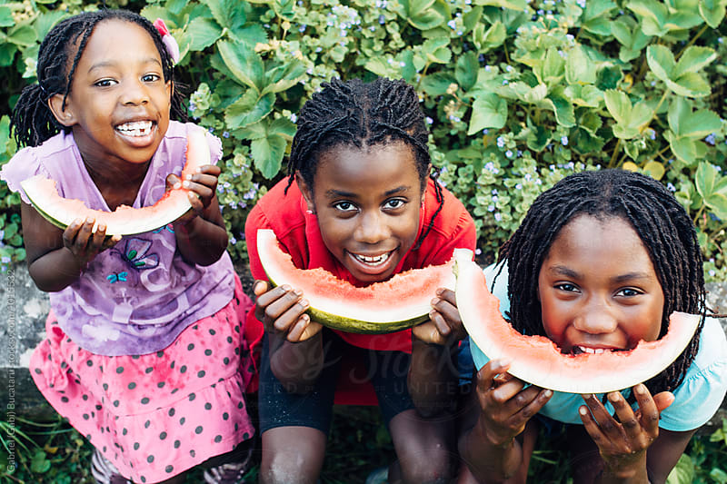 Three laughing black girls eating watermelon