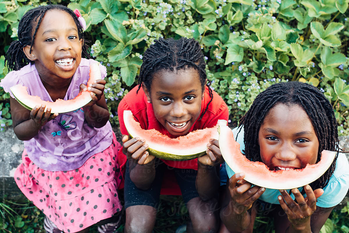 Three laughing black girls eating watermelon