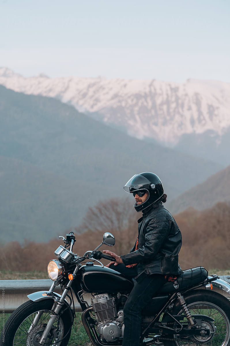 Man sitting on motorcycle near mountains