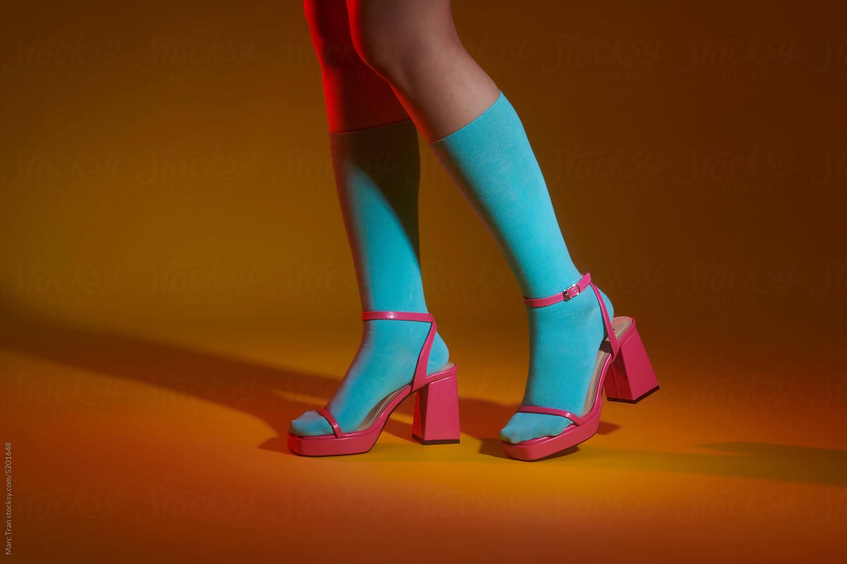 Crop of woman feet wearing pink heels and blue socks.