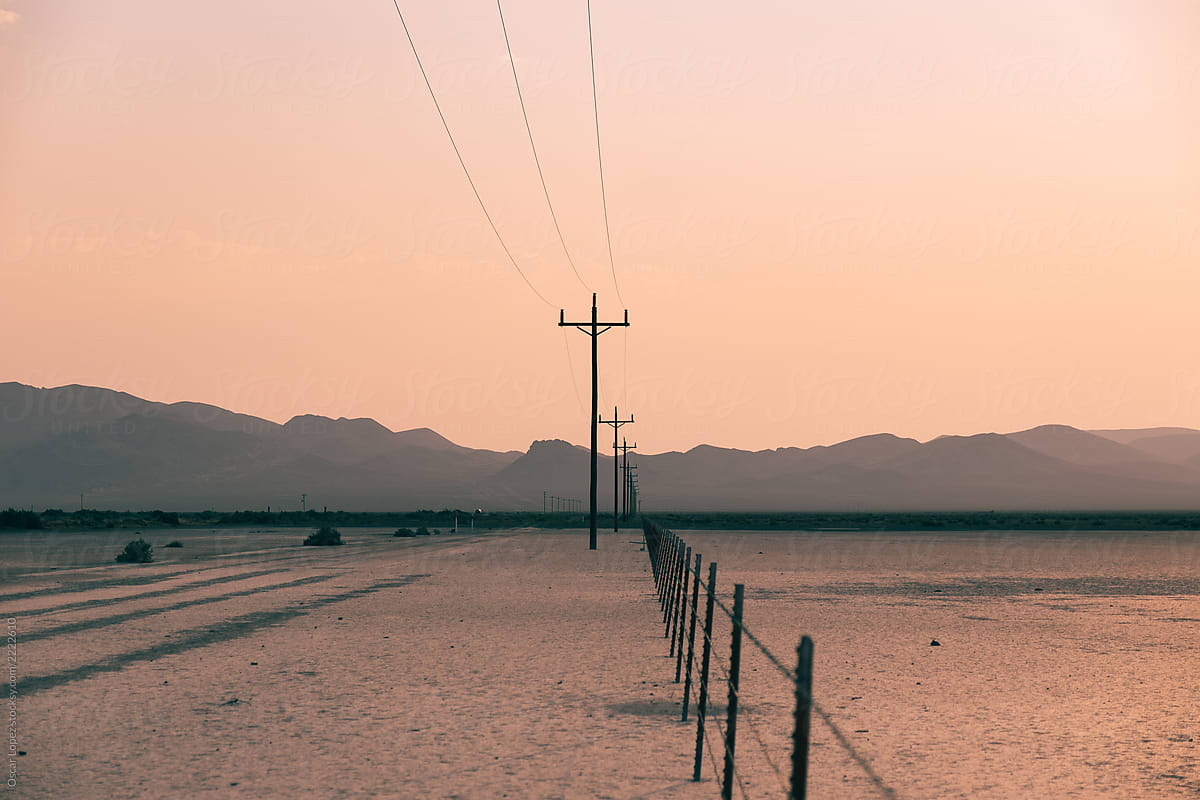 Power lines and fence on a flat desert bed