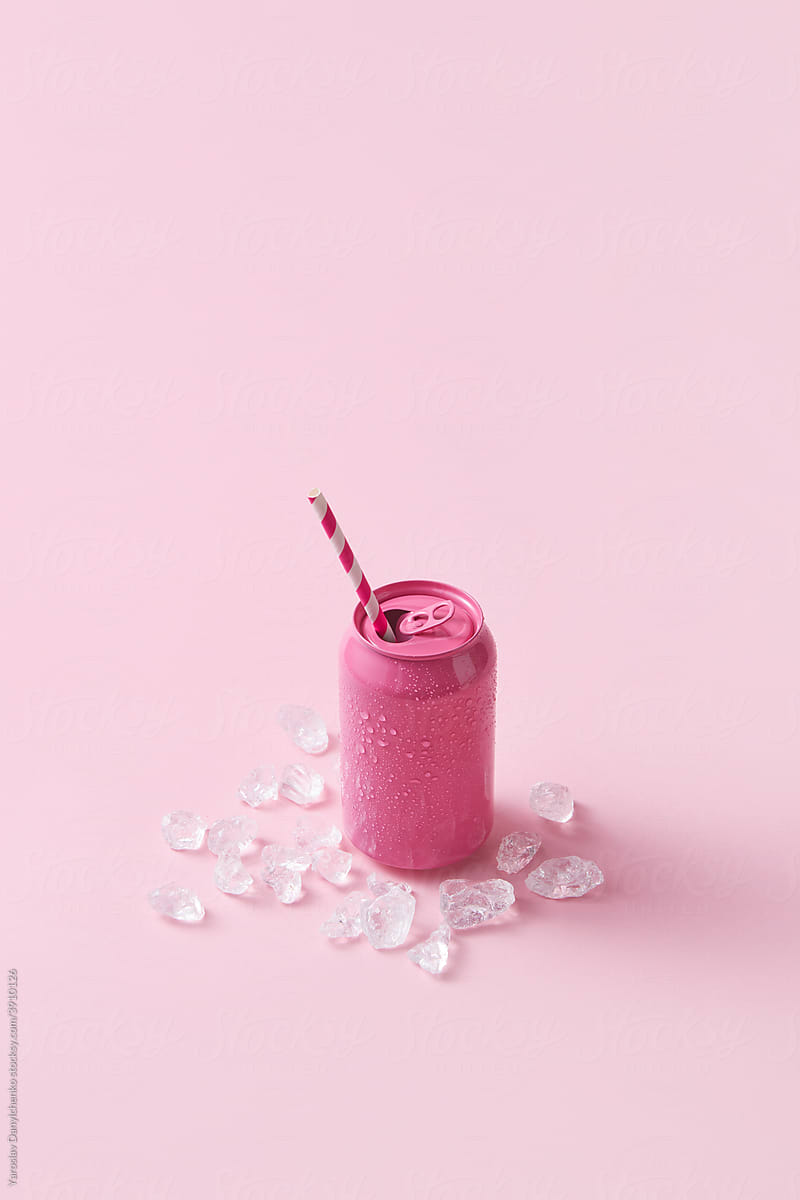 Pink soda can with paper straw and ice cubes