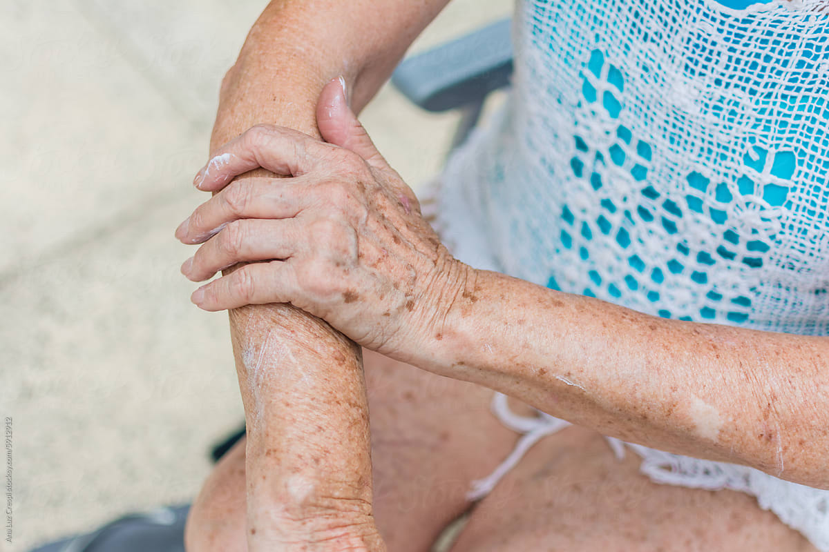Senior woman applying sunblock lotion to her arm