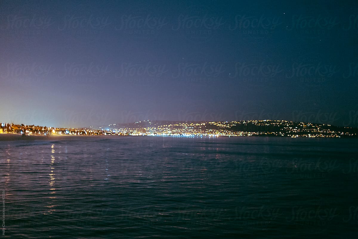 Ocean view of lights along coastline and sky with stars