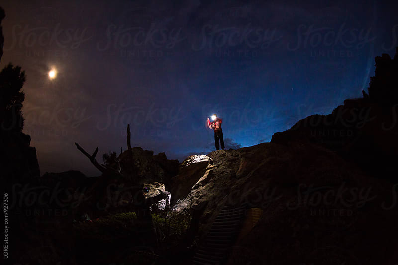 Climber Coils a Rope on the Summit at Night in the Light of the Moon
