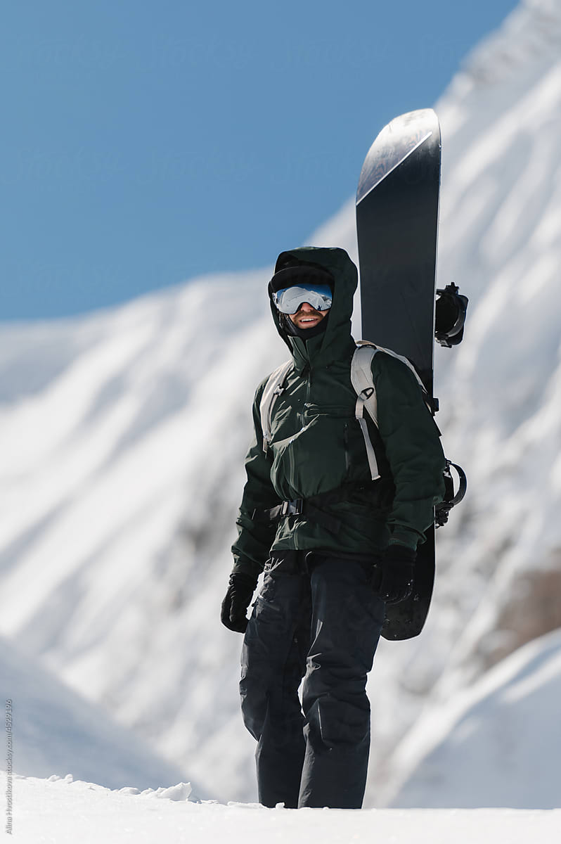 Male snowboarded against snowy mountains