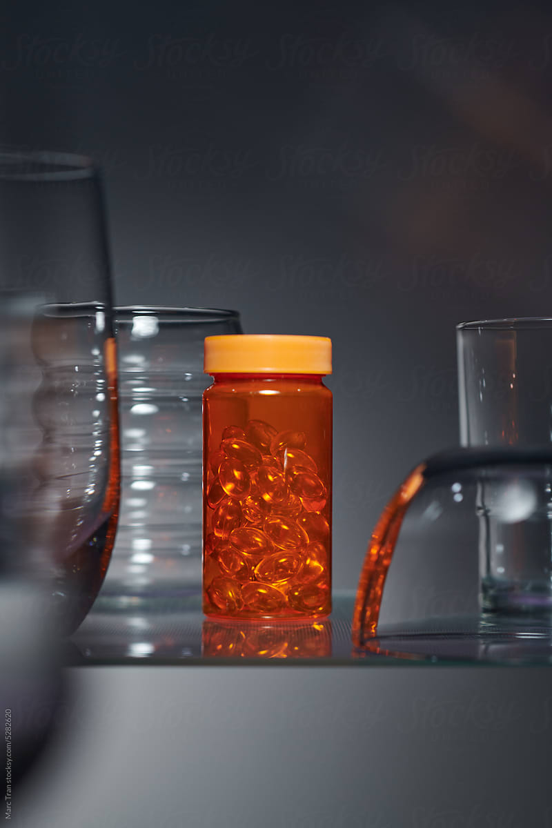 oil capsules and orange jar stand on glasses podium on the background
