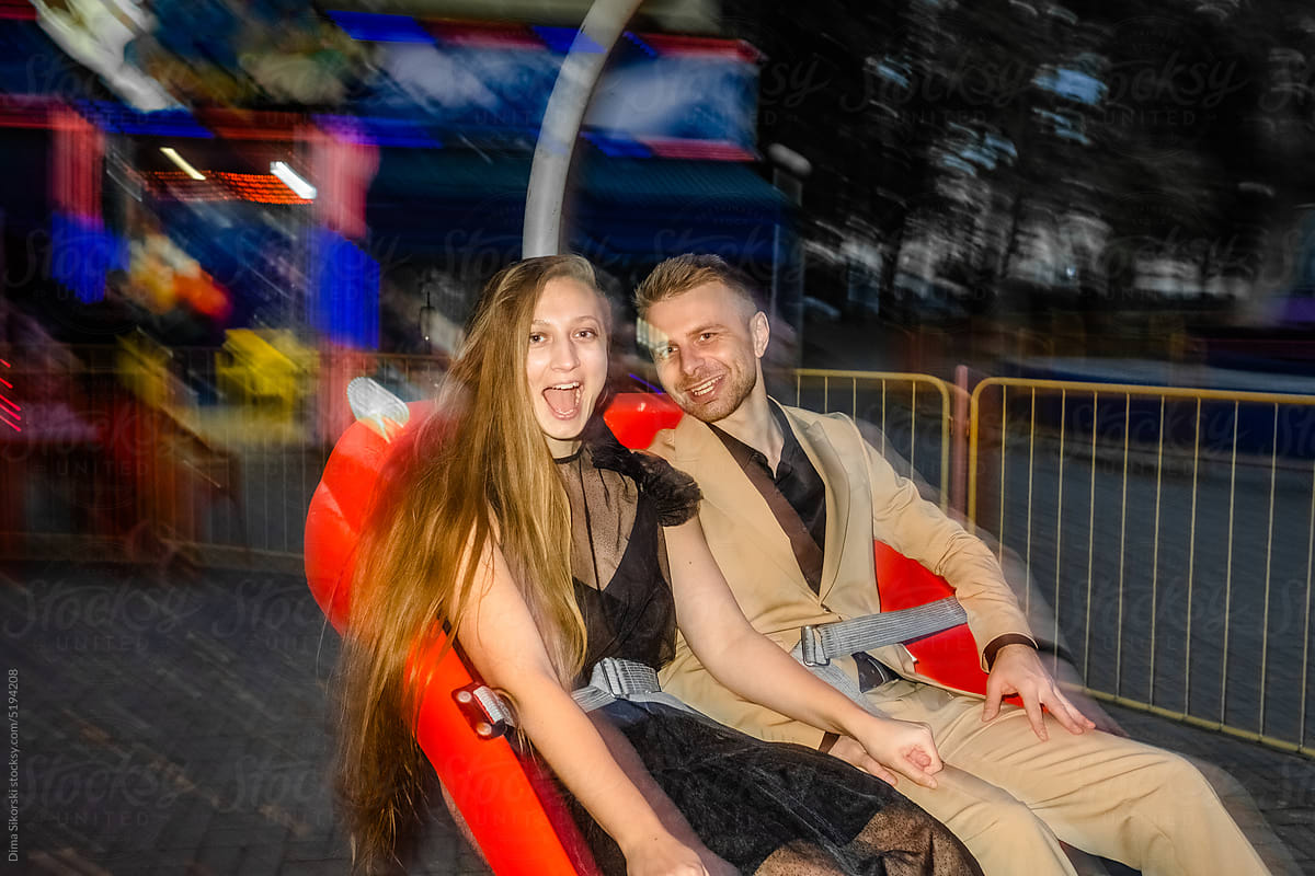 A frightened joyful couple in love rides at night on an attraction