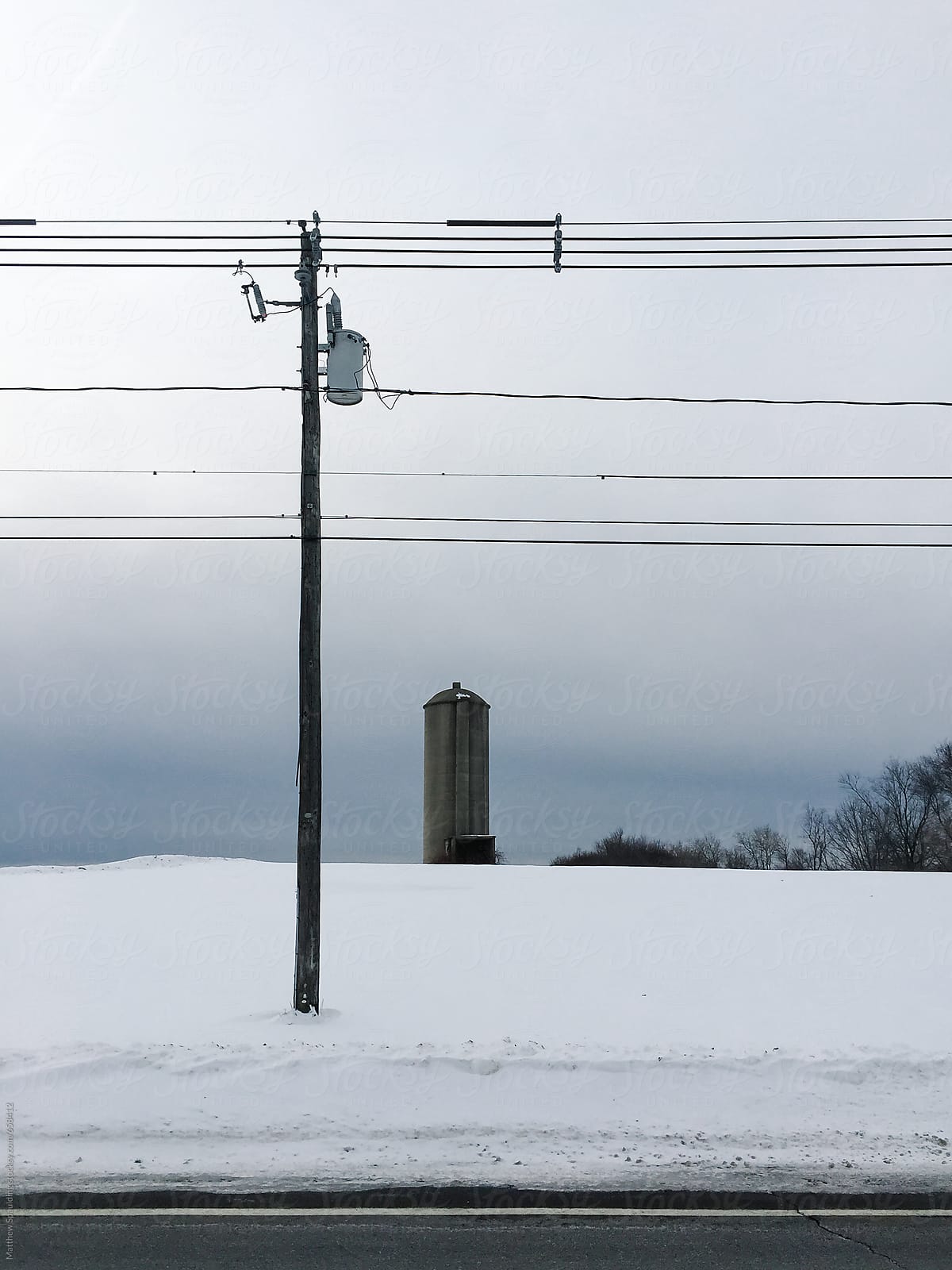Cement silo telephone wires on roadside in winter