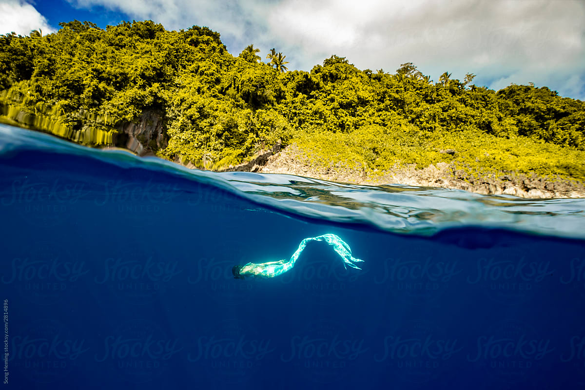 A mermaid diving half underwater