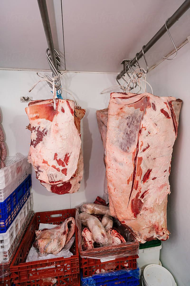 Raw meat hanging on racks in slaughterhouse