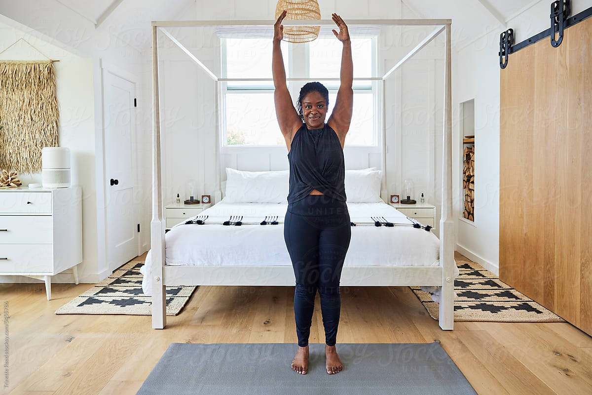 Mature Black woman stretching doing yoga at home in bedroom