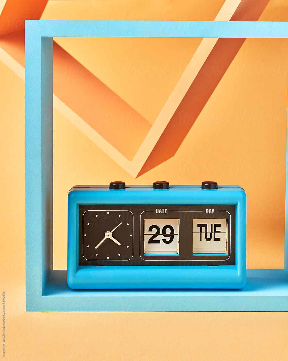 Vintage blue flip clock on wooden square shelf on an yellow background with copy space.