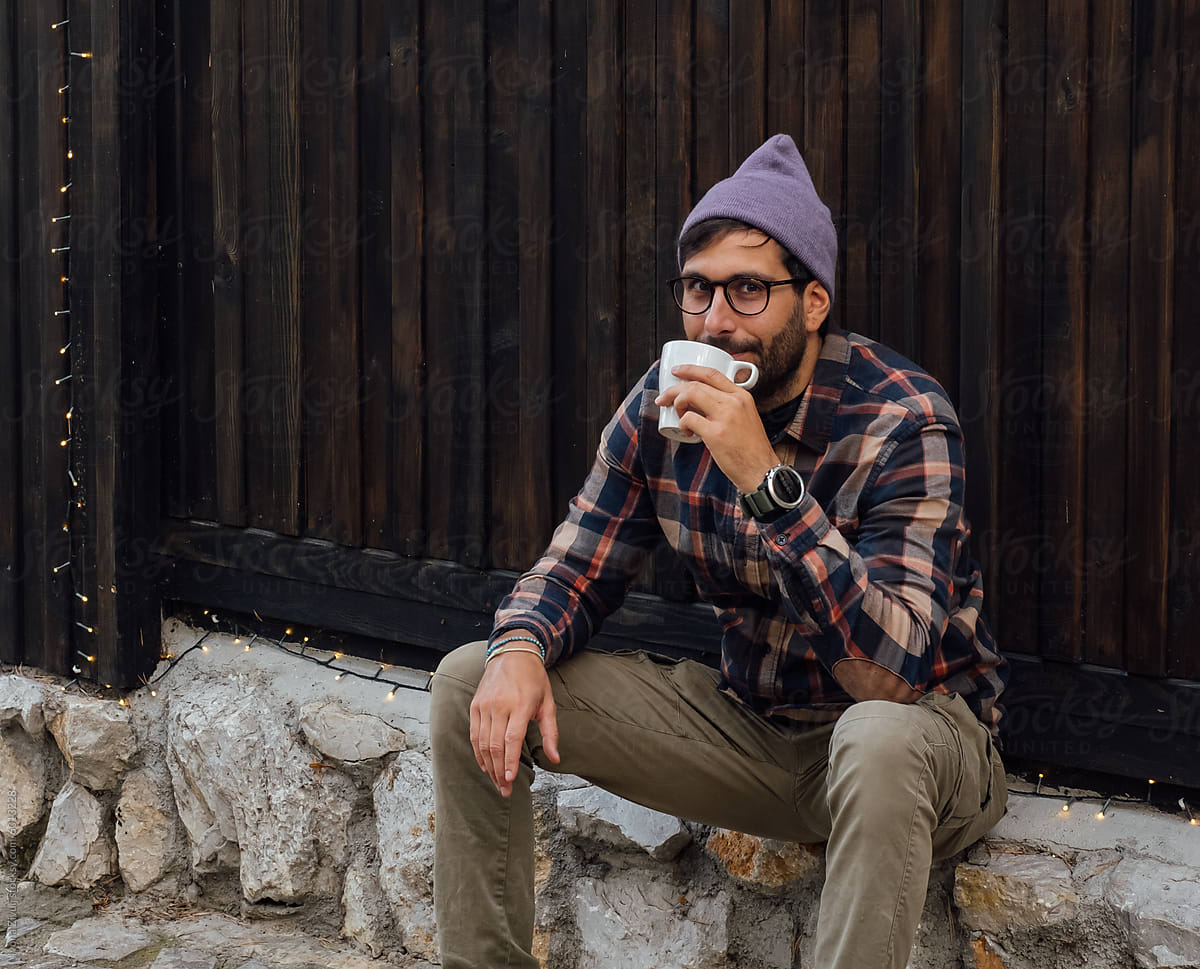 Man Sitting In Front of Cabin With Coffee Cup
