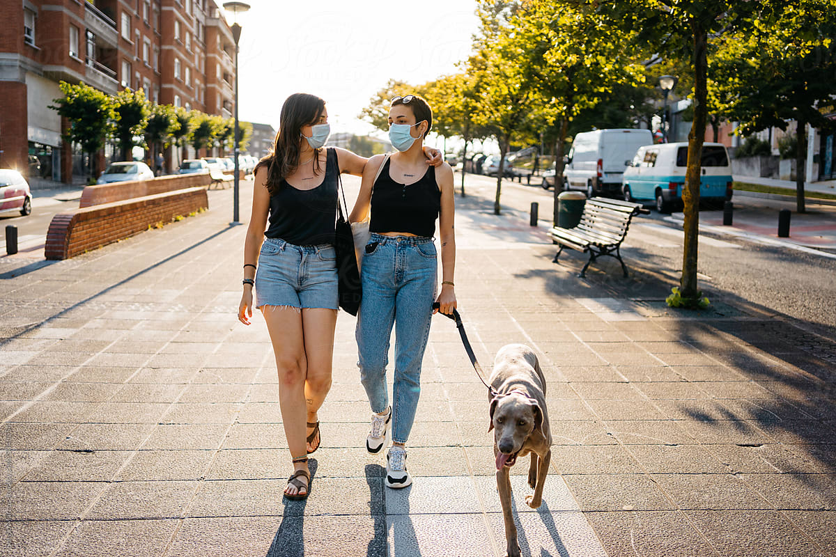 Girlfriends in masks walking with dog