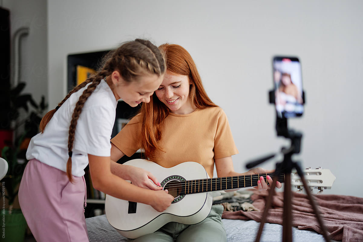Sisters together playing on guitar and recording video