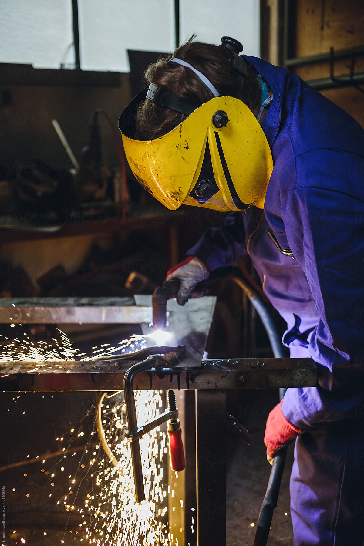 metal worker with plasma cutter and yellow protection mask