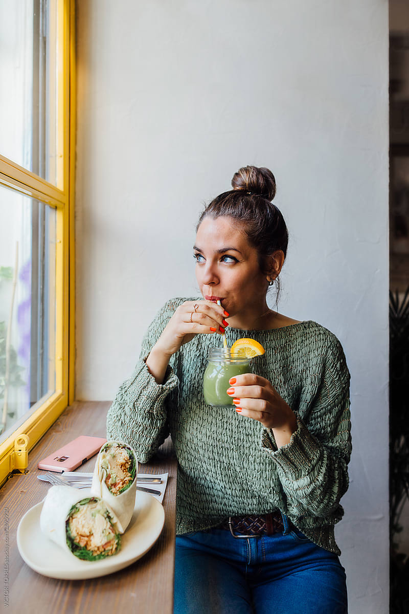 Young casual woman eating healthy food in cafe