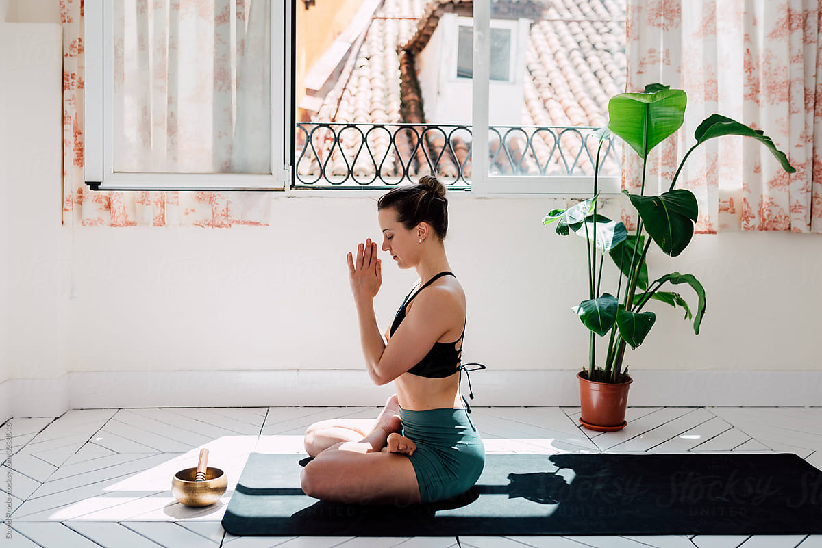 Relaxed woman meditating in lotus pose with singing bowl