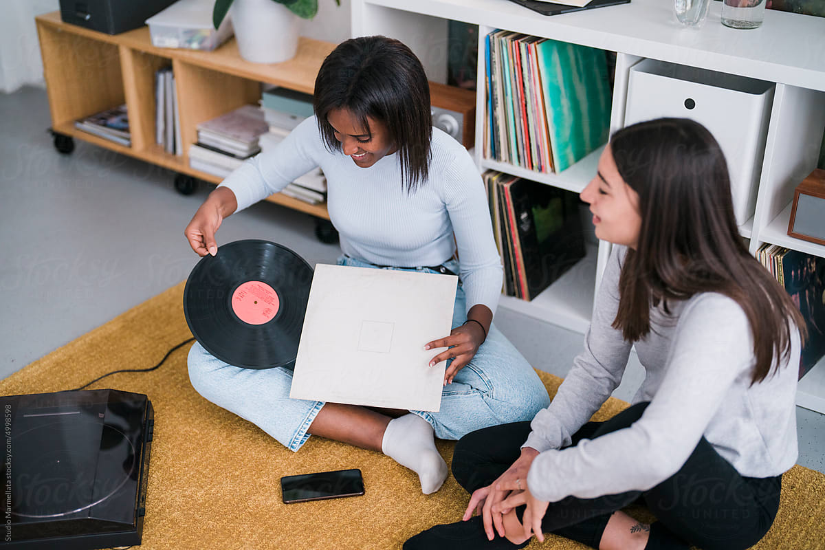Happy diverse ladies choosing vinyl records on floor