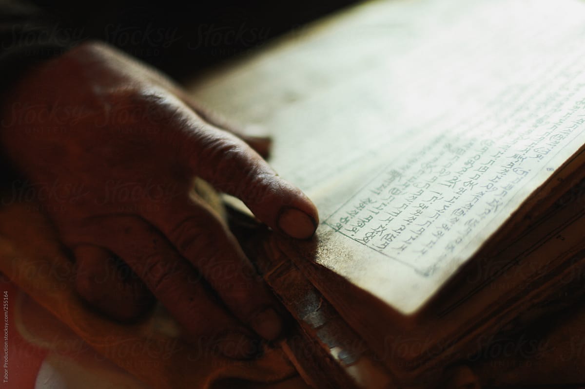 Aged hand on religious scriptures