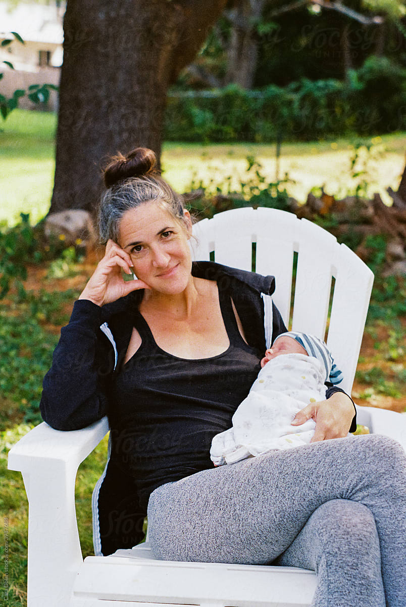 Postpartum Life-Mother Sits Outdoors with New Baby