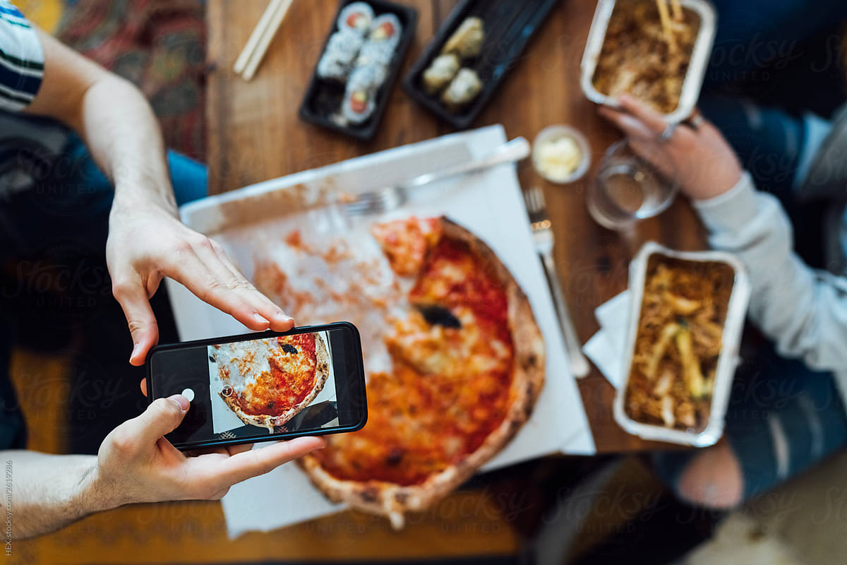 An anonymous person taking a picture of a Pizzza with his Smartphone