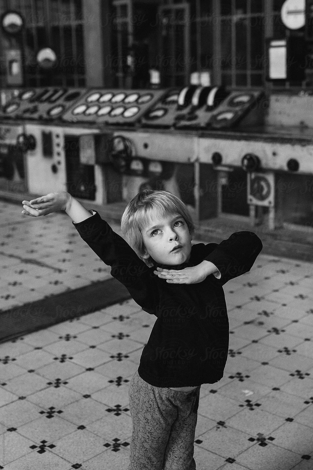 A cute boy child dances in a disused power station.