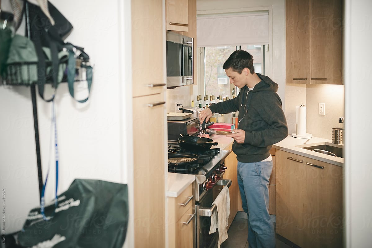 Young Male University Student Makes Egg on Toast as Breakfast in Kitchen