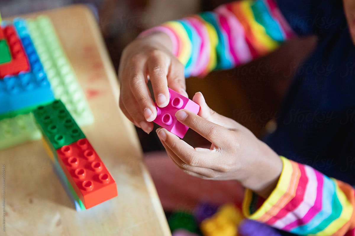 Closeup of a child\'s hands as she plays with lego blocks