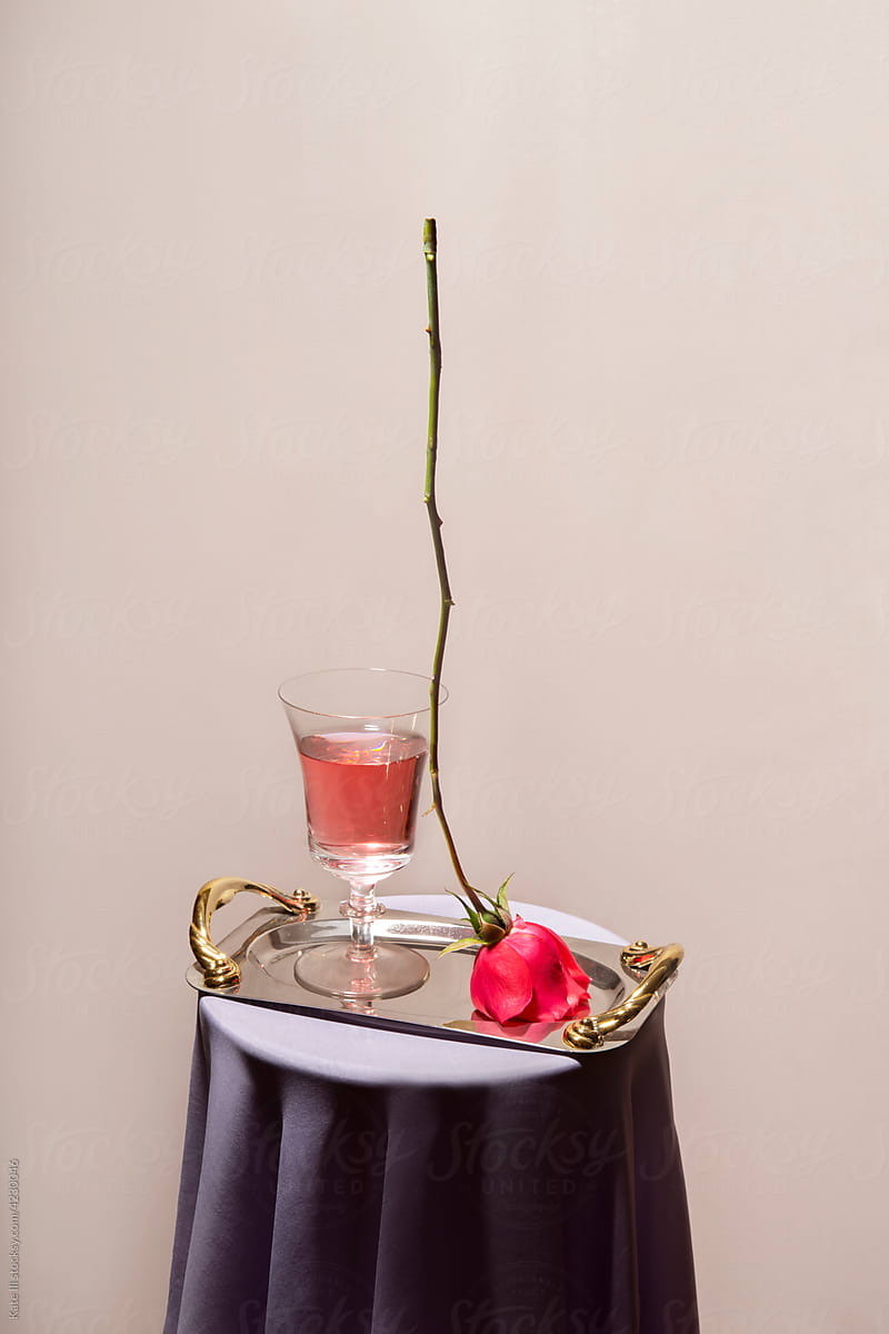 A glass and a rose on a tray