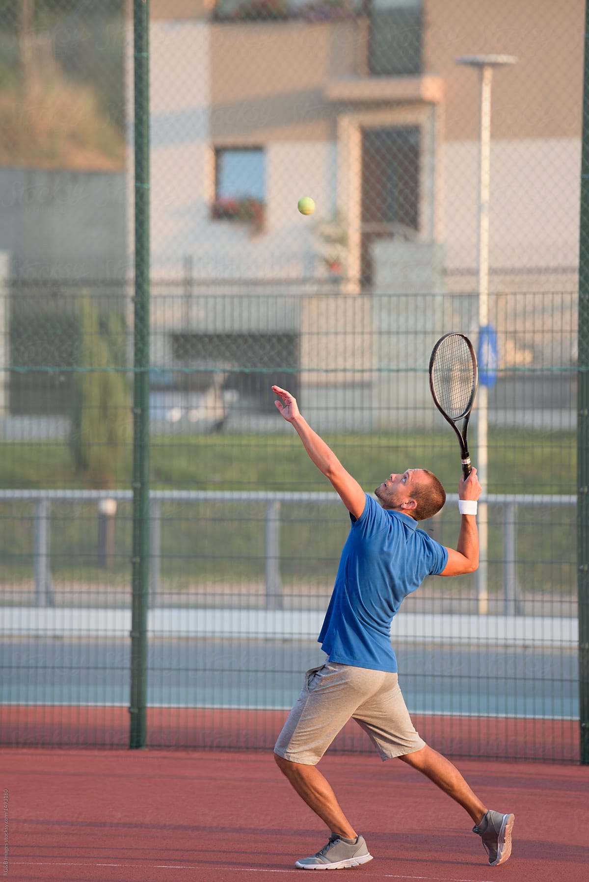 Man serving while playing tennis outdoor on clay court