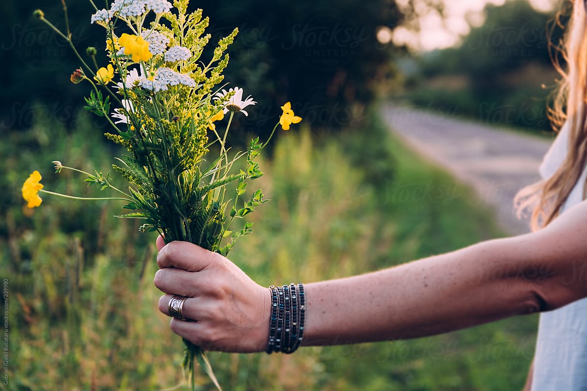 Woman Holding a Bouquet of Wild Flowers By A Road Side At Sunset