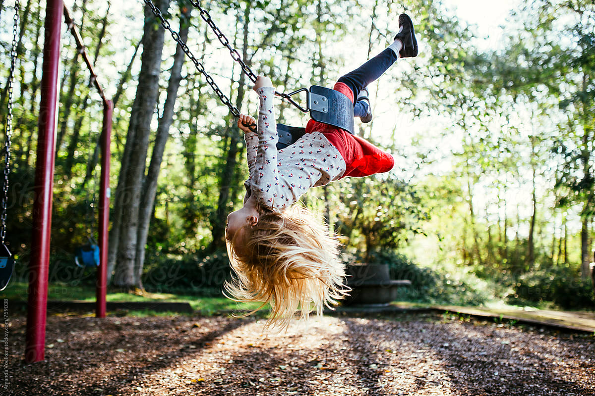 A Little Girl Swings Upside Down On the Swing