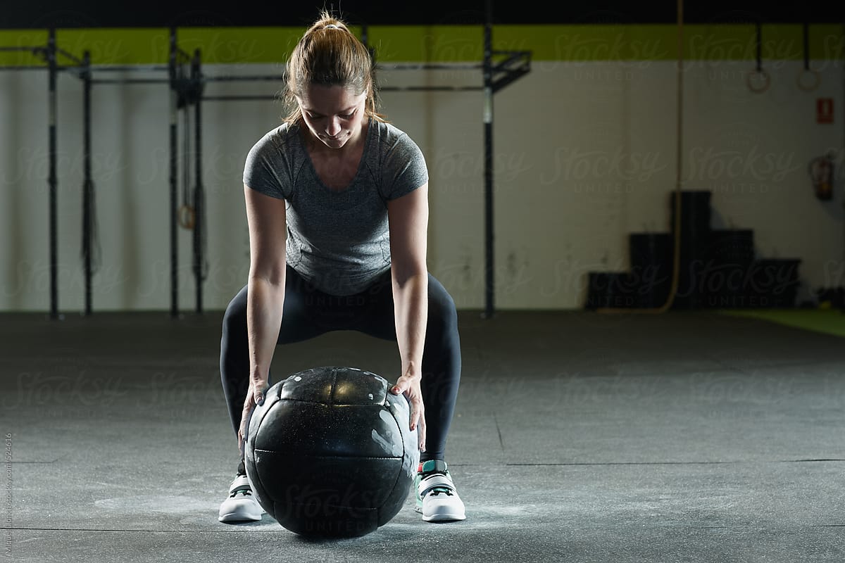 Fit woman getting ready to lift a heavy training ball