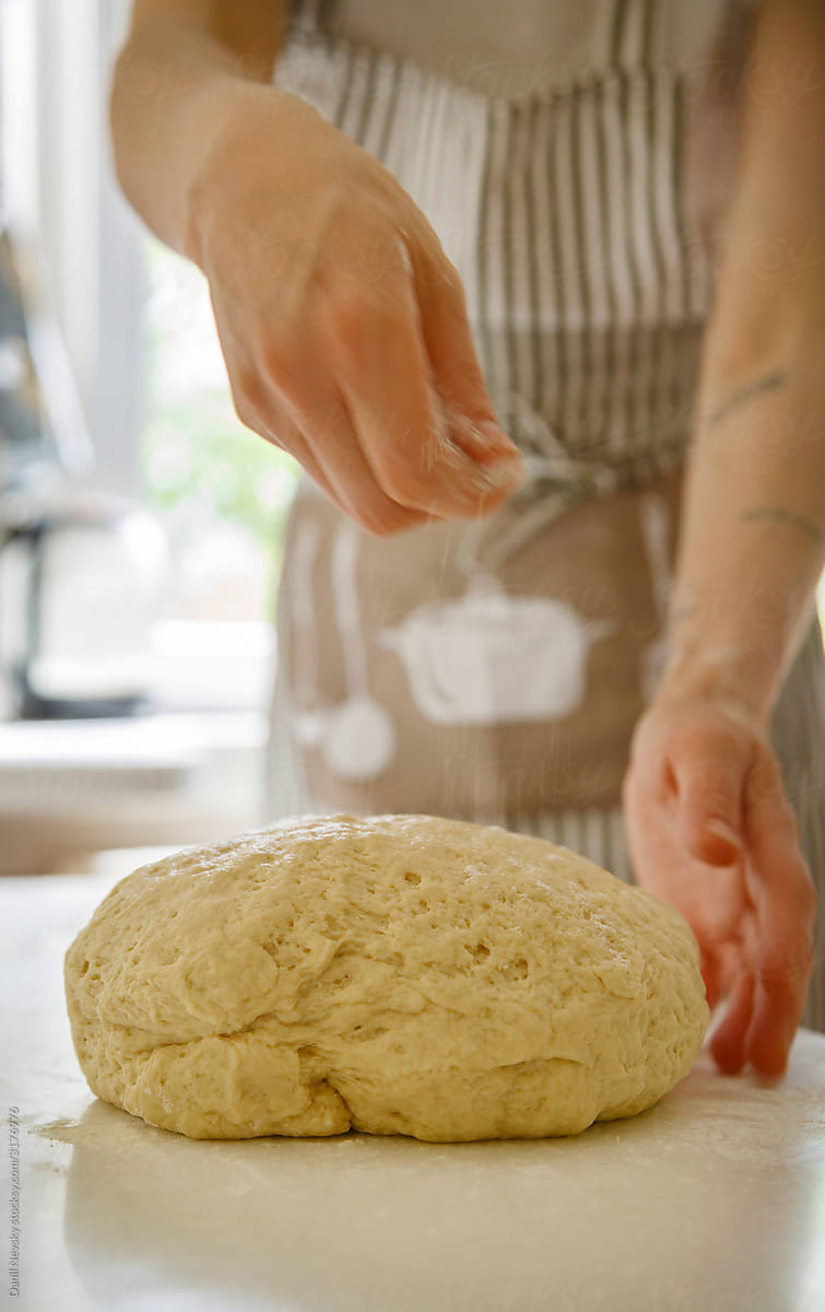 Crop housewife adding flour to dough