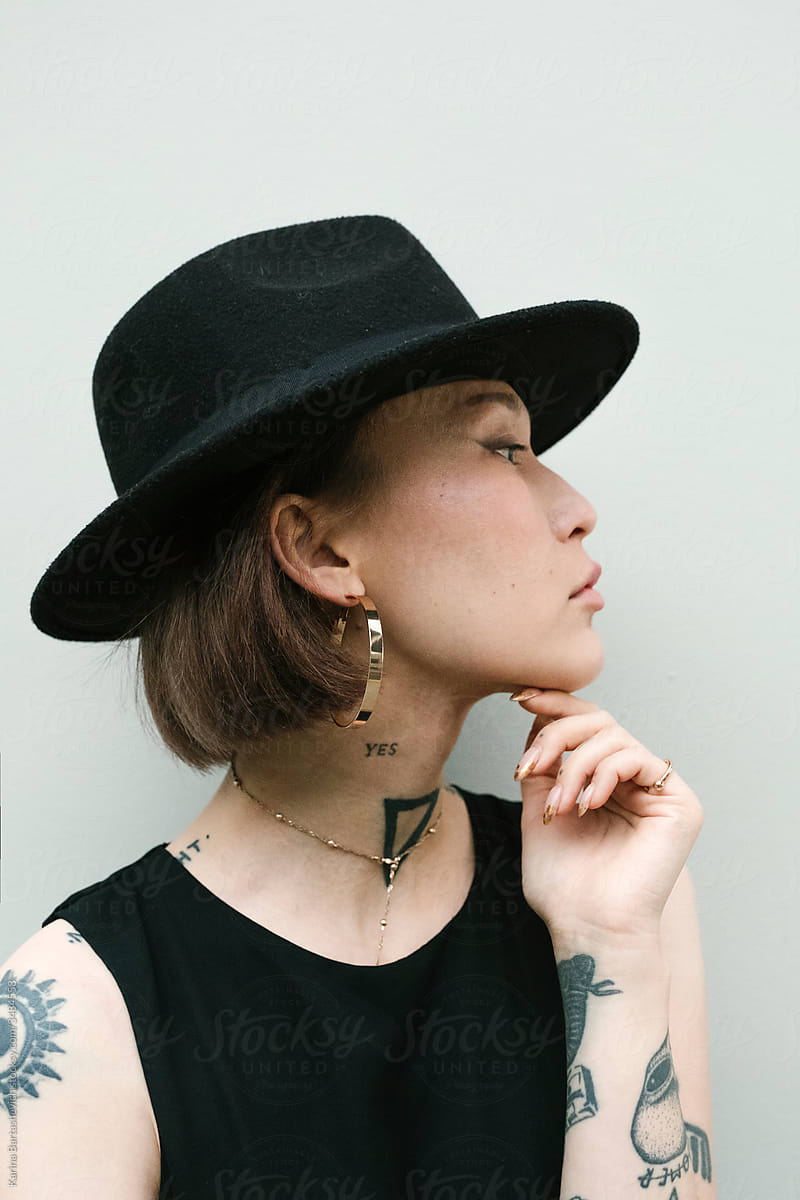 portrait of a girl with tattoos on her arms and neck and stylish accessories in profile