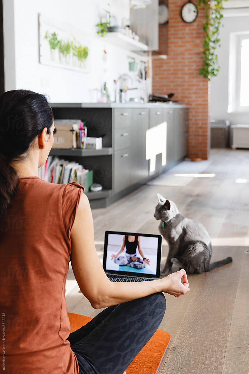 Brunette woman taking an online yoga class at home