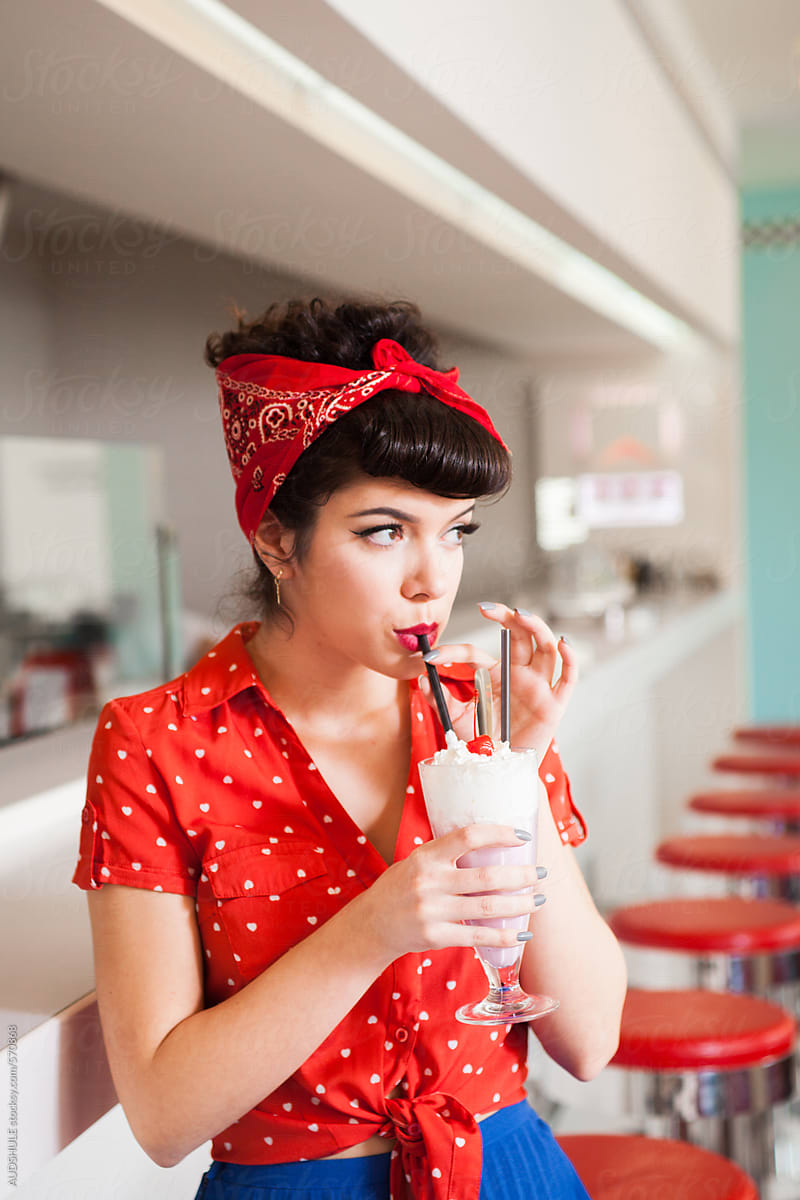 Close Up Of Rockabilly Woman Drinking Milkshake At Diner. by