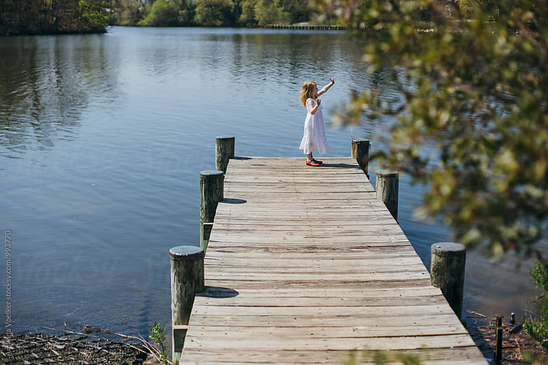 A little Girl Waves at the end of a Dock