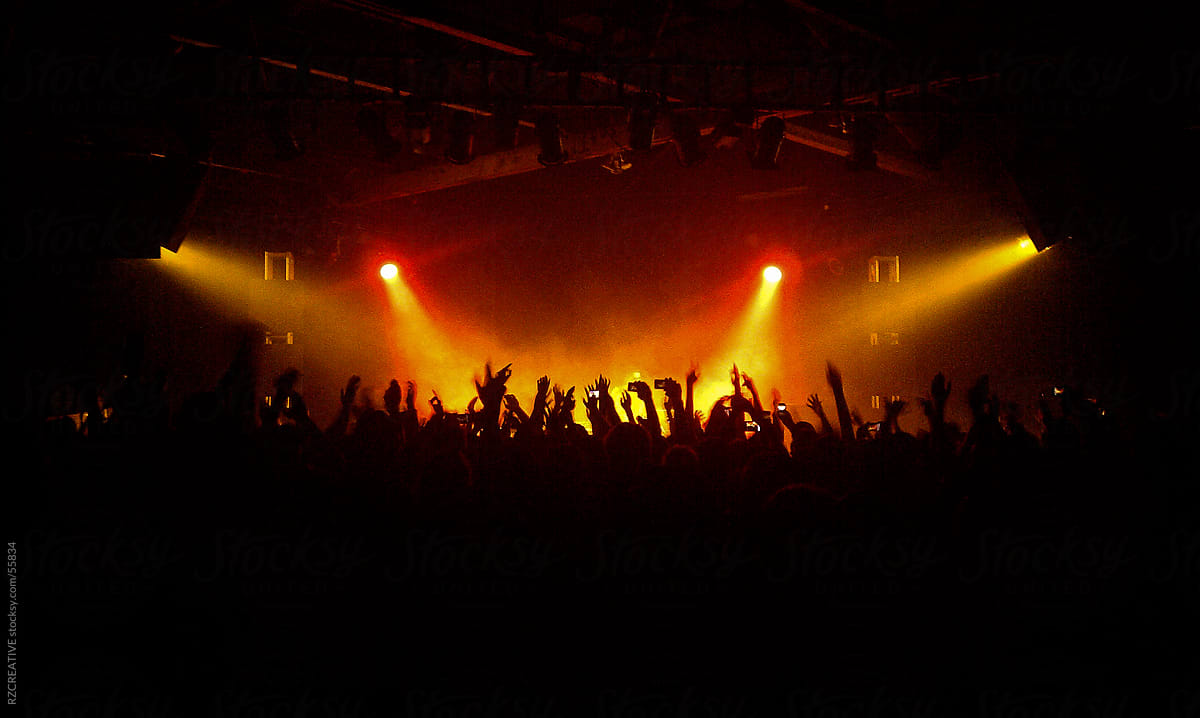 Red and orange concert lights shine on a stage during a concert.