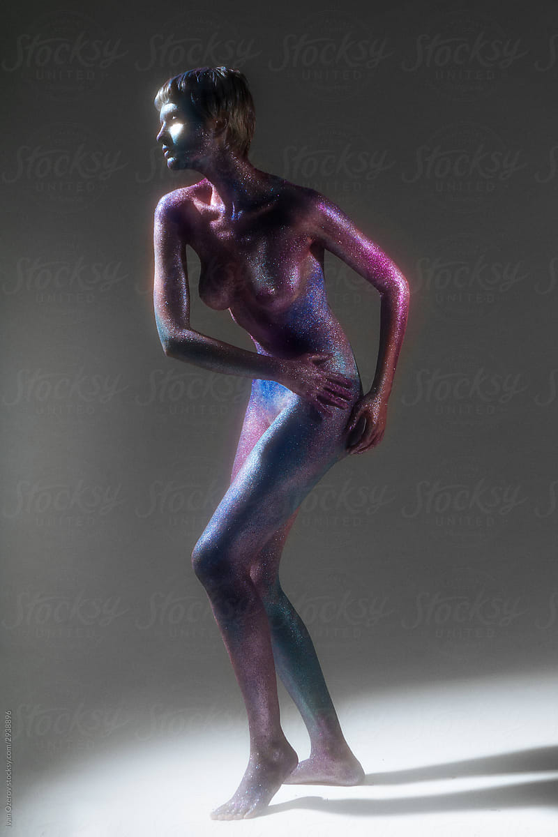 nude woman with space bodypainting poses in a dance pose on a white cyclorama