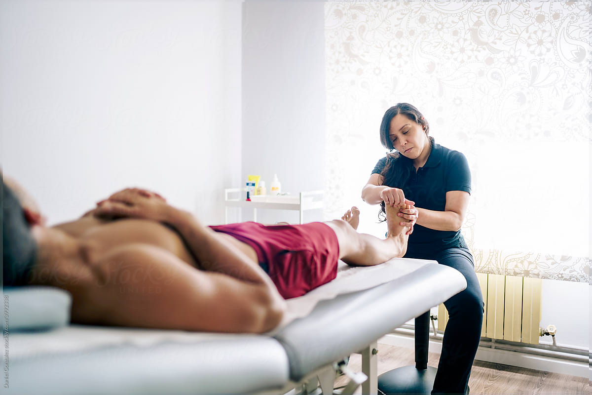 Chiropractor massaging feet of client in modern clinic