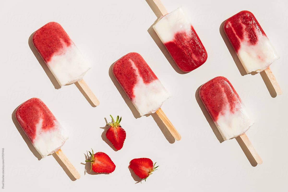 Homemade strawberry ice cream popsicles on white background